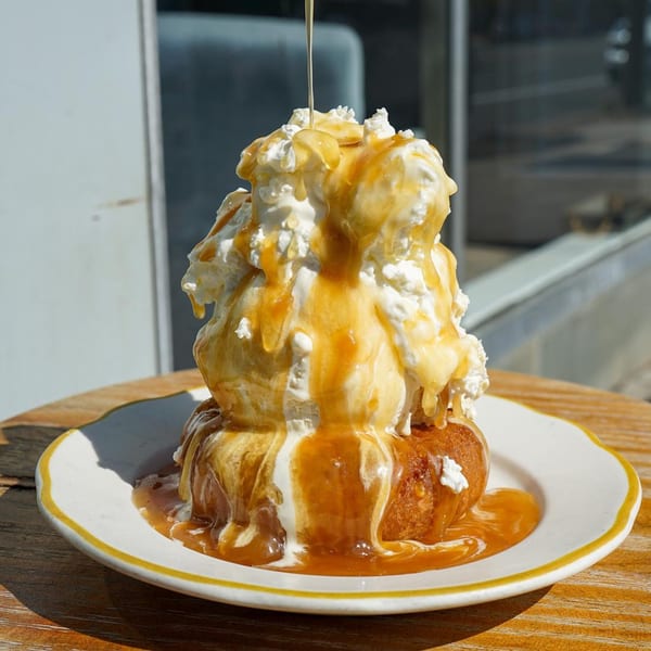 A Hildebrandt's ice cream sundae with whipped cream and caramel sauce on a white plate.