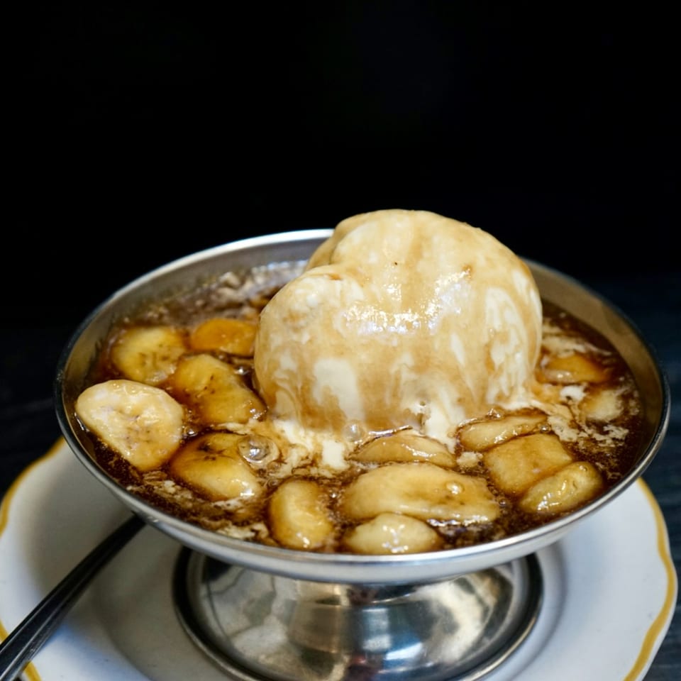 Hildebrandt's banana split with vanilla ice cream and caramel sauce in a metal bowl.