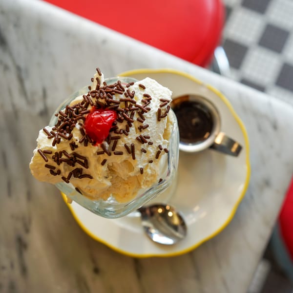 Hildebrandt's vanilla ice cream sundae with whipped cream, chocolate sprinkles, and a cherry.